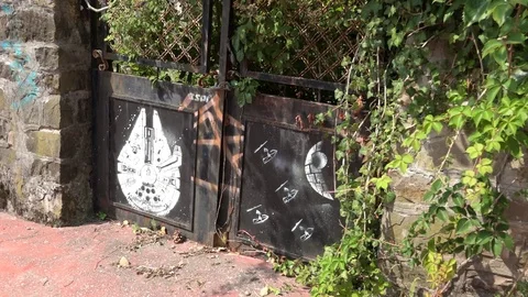Abandoned iron gate with star wars graffiti, millennium falcon and death star Stock Footage 79611464