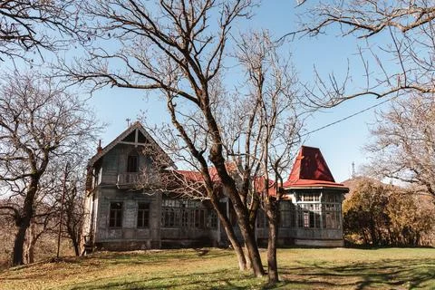 Abandoned mansion surrounded by bare trees on a clear day in a remote Stock Photos