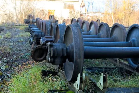 Abandoned railway yard features rusty train wheels among overgrown vegetation in Stock Photos