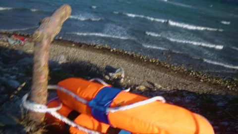 Abandoned refugee lifejacket plastic garbage in seaweed Stock Footage 145925497