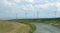 Abandoned road near modern windmills rotating on wind farm. Future technology 4k or 4k+ Resolution