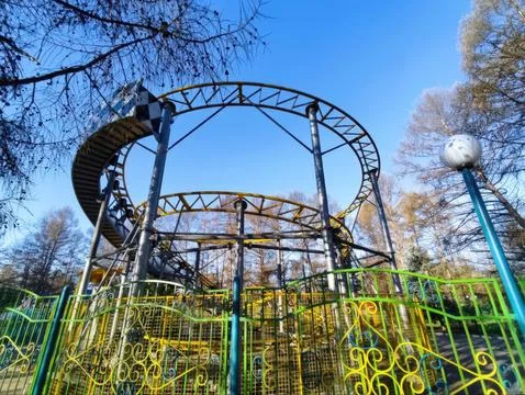 Abandoned roller coaster surrounded by trees in a quiet amusement park Foto stock