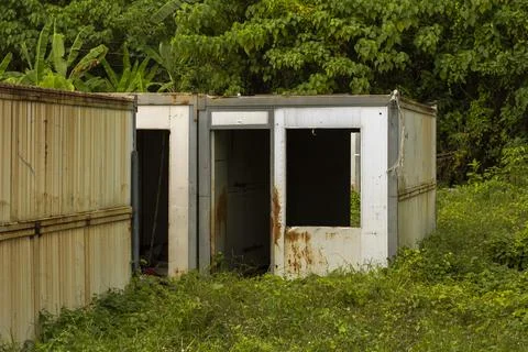 Abandoned Rusted Modular Metal Structure Surrounded by Dense Vegetation Stock Photos