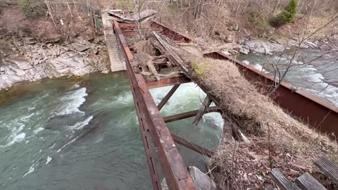 Abandoned rusty bridge over fast river in forested mountain area Stock Footage 312293049