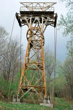 Abandoned rusty cable-way pillar in forest - old technology Stock Photos