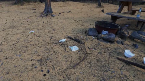 Abandoned sandy campsite with trash, fire pit, and picnic table Stock Footage 346919429