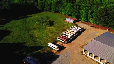 Abandoned School Buses Lined Up Beside Rural Building in Grassy Lot Stock Footage 307158831