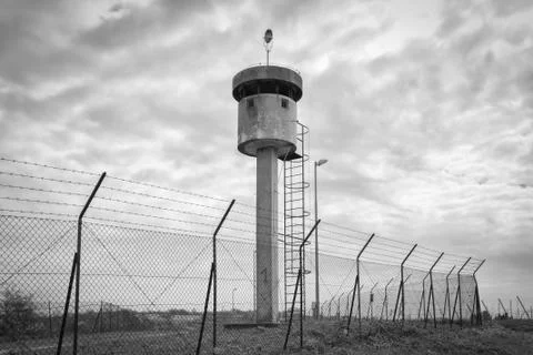 Abandoned sentry box tower isolated by a net with barbed wire. Stock Photos