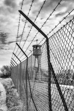 Abandoned sentry box tower isolated by a net with barbed wire. Stock Photos