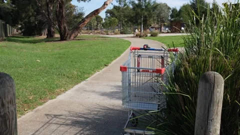 Abandoned shopping trolley on a park footpath in Australia near playground Stock-Footage 336033161