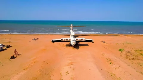 Abandoned soviet lun class ekranoplan warplane resting on sandy beach aerial Stock Footage 343695817