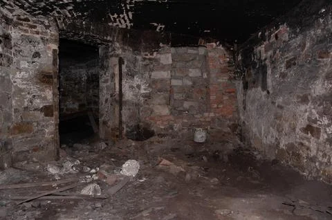 Abandoned Stone Basement Interior With Charred Brick Walls And Debris Scatt.. Stock Photos