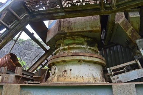 Abandoned stone crusher plant with rusted machinery and overgrown vegetation. 스톡 사진