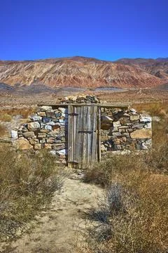 Abandoned Stone Structure Desert Path and Mountain Landscape Under Blue Sky Foto stock