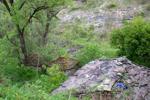 Abandoned stone structures nestled in a lush green valley surrounded by roc.. Stock Photos