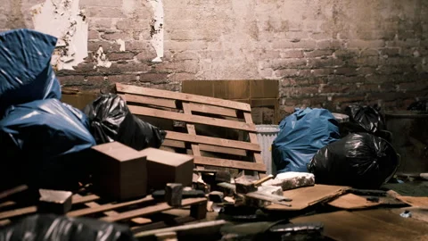 Abandoned storage room filled with garbage bags and wooden pallets at night Stock Footage 304467773