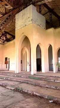 Abandoned structure with beige Arabic-style arches shows decay, rusted beams Stock Photos