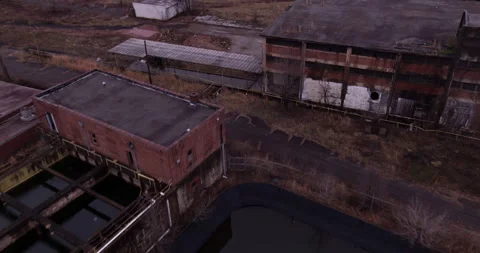 Abandoned Structures flyover with Smokestack Bird Muddy Waterfall Stock Footage 278254359