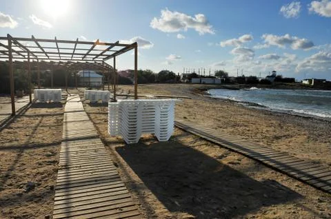 Abandoned sunny empty beach resort with sun beds during cold weather off seas 스톡 사진