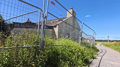 Abandoned Welsh seafront cottage surrounded by security wired fencing and Video stock 339088438