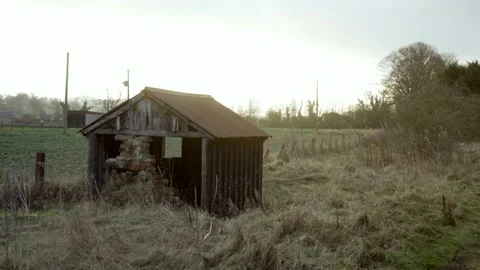 Abandoned wooden hut with grassy fields in background at golden hour Stock Footage 169057286