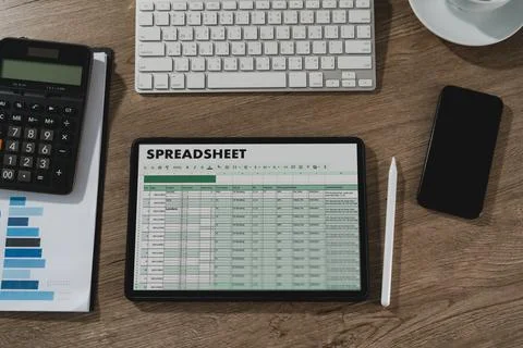 Ablet displaying spreadsheet data on desk with calculator, keyboard, smartp.. 스톡 사진