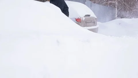Abnormal snowfall, climate change, a man digs a car out of the snow Video stock 104546087