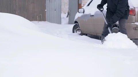 Abnormal snowfall, climate change, a man digs a car out of the snow Stock Footage 104546112