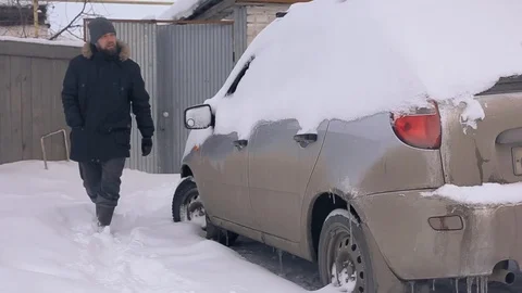 Abnormal snowfall, climate change, a man digs a car out of the snow Stock Footage 104546202