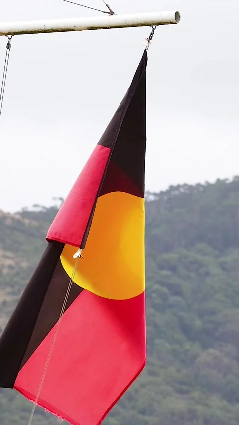 Aboriginal Flag Waving in Wind Against Lush Green Mountain Backdrop Stock Footage 326088666