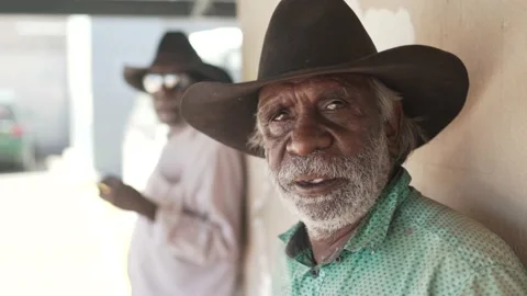 Aboriginal man gazing into camera while a truck passes in outback Australia Stock Footage 193988079