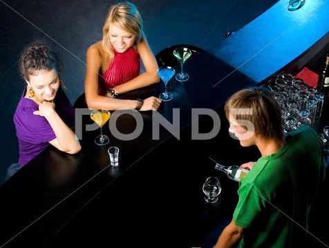 Above angle of glamorous girls in the bar with barman near by Stock Photos