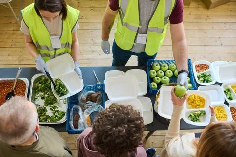 Above angle of two volunteers in uniform spreading food among refugees Stock Photos