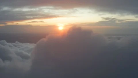 Above a bed of clouds with the sun peaking on a red sunset backdrop Stock Footage 120747369