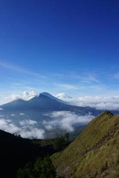 Above Cloud Nine, Mount Batur's Peak, Asian Man Trekker under Azure Sky and.. Stock Photos