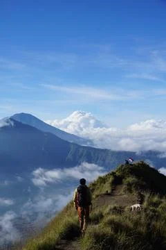 Above Cloud Nine, Mount Batur's Peak, Asian Man Trekker under Azure Sky and.. Stock-Fotos