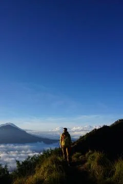 Above Cloud Nine, Mount Batur's Peak, Asian Man Trekker under Azure Sky Stock Photos