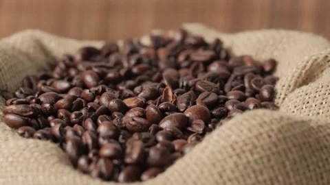 From above, dark coffee beans fall into an eco-bag made of burlap. Vídeos de archivo 154085606