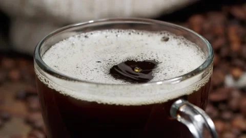 From above drop falling into cup of freshly brewed coffee with bubbles on table Stock Footage 146869302