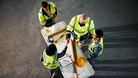 Above, engineer and shaking hands on site with blueprint, design approval and Stock Photos
