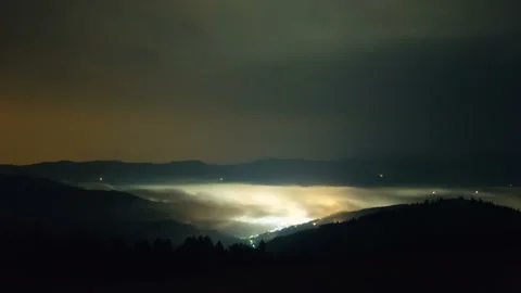 Above flowing cloud waves. Time-lapse of clouds over glowing town in Carpathian Stock Footage 132176053