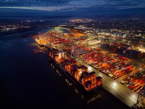 Above Hapag-Lloyd container ship at dusk at illuminated Southampton Docks aerial Stock Photos