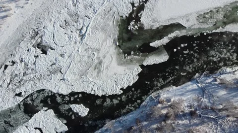 Above mostly frozen river looking down with ice floating Stock Footage 310568804