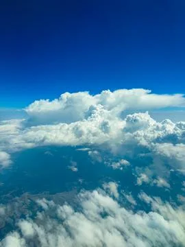 Above a patchwork of earth and sky, fluffy white clouds float serenely agains Stockfoto's