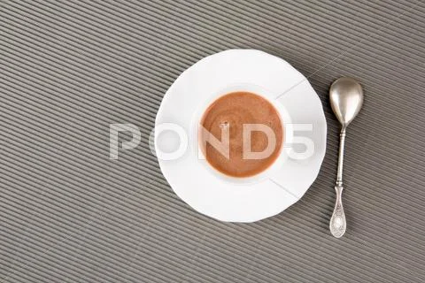 Above shot of cappuccino in porcelain cup with small spoon near by Stock Photos