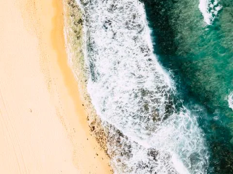 Above vertical view of blue ocean waves and yellow sandy beach - summer holid Stock Photos