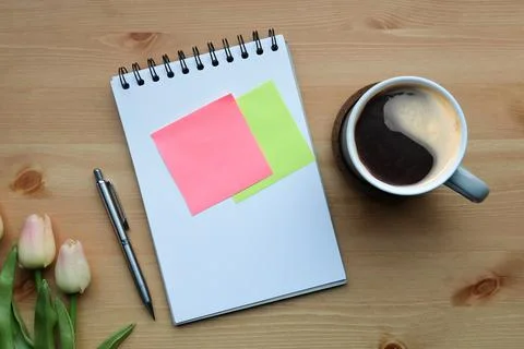 Above view coffee cup, notepad, sticky notes and pink tulips on wooden table. Foto stock