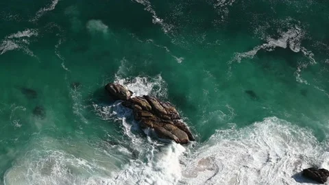 Above view of crashing ocean waves on a rock with turquoise water Видео 166553756