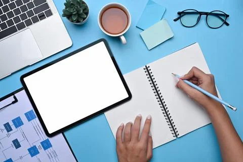 Above view creative woman using digital tablet and making notes on notebook. 스톡 사진