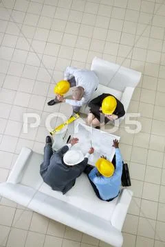Above view of four engineers sitting at table and planning a housing project Stock Photos